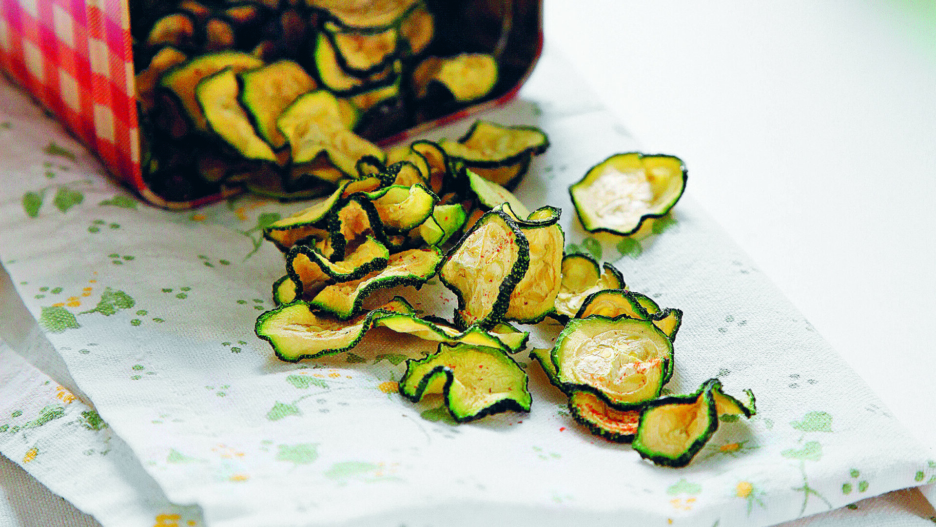 Snack vegano e senza glutine a base di chips di zucchine essiccate, una ricetta facile per far mangiare le verdure ai bambini.