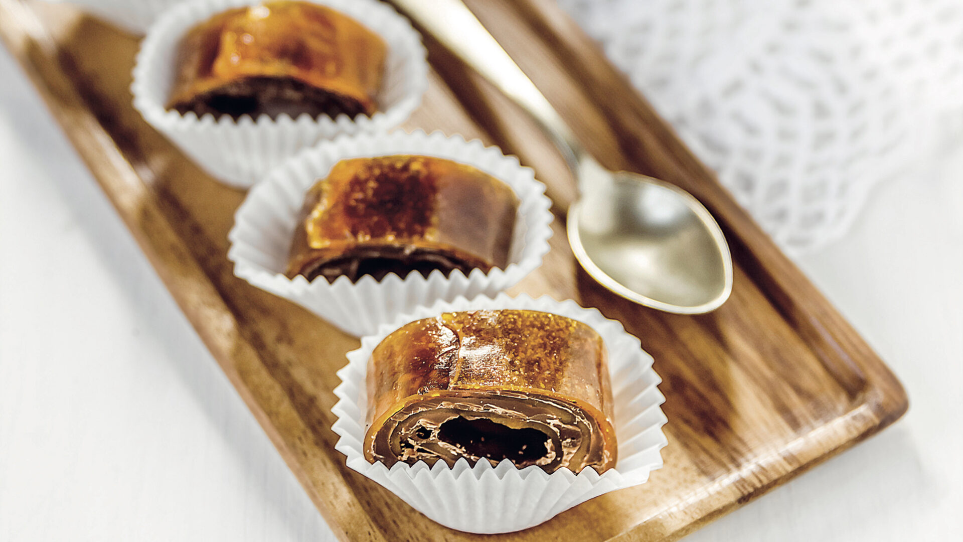 Pasticcini sani e vegani realizzati arrotolando fogli di fruit leather di cachi essiccata con uno strato di cioccolato fondente.